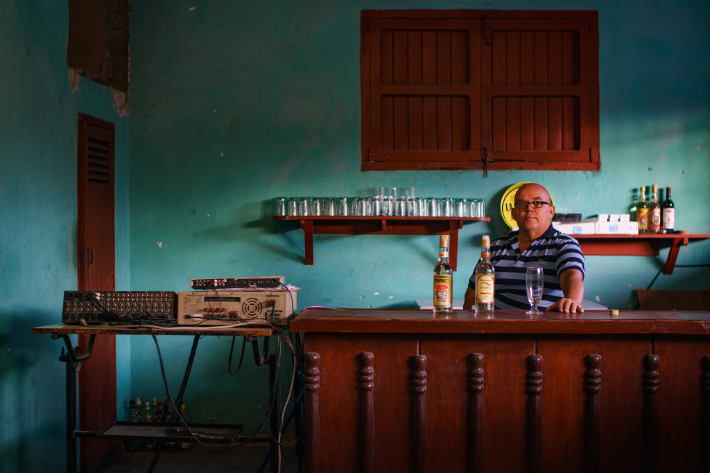 A bar owner poses as the late afternoon sun sets through the window in Ciego De Avila. Photographed with a Tamron 45mm f/1.8 at 1/40 seconds and f/1.8.