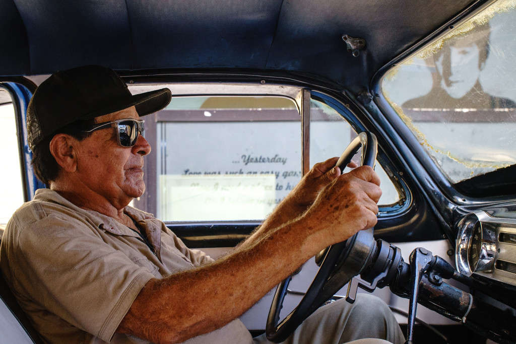 A man sits in his car as John Lenon keeps a watchful eye at a Beatles-themed bar in Holguin. Photographed with a Tamron 24-70 f/2.8 at 1/400 and f/4.5.