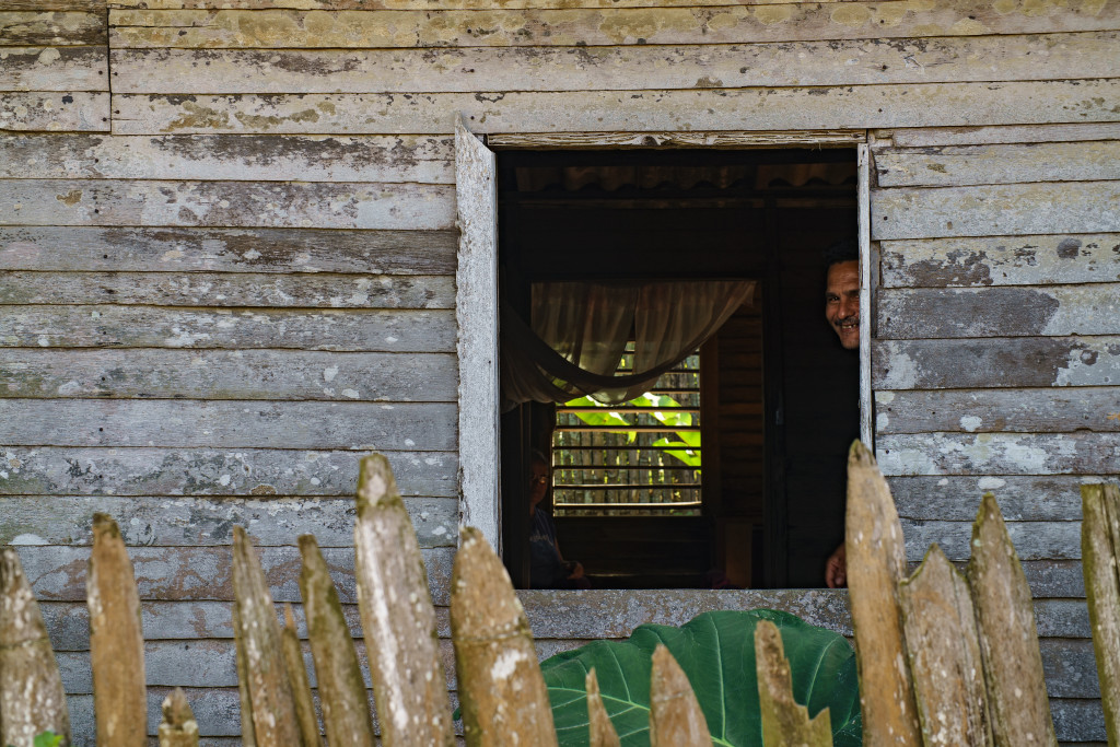 A man smiles out of his window in Baracoa. Photographed with a Tamron 24-70mm f/2.8 at 1/100 and f/5.6.