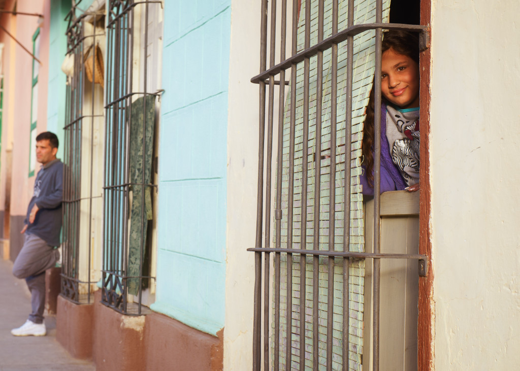 A young girl peers out of her blinds in the city of Trinidad. Tamron 24-70mm, 1/60 second, f/4.5